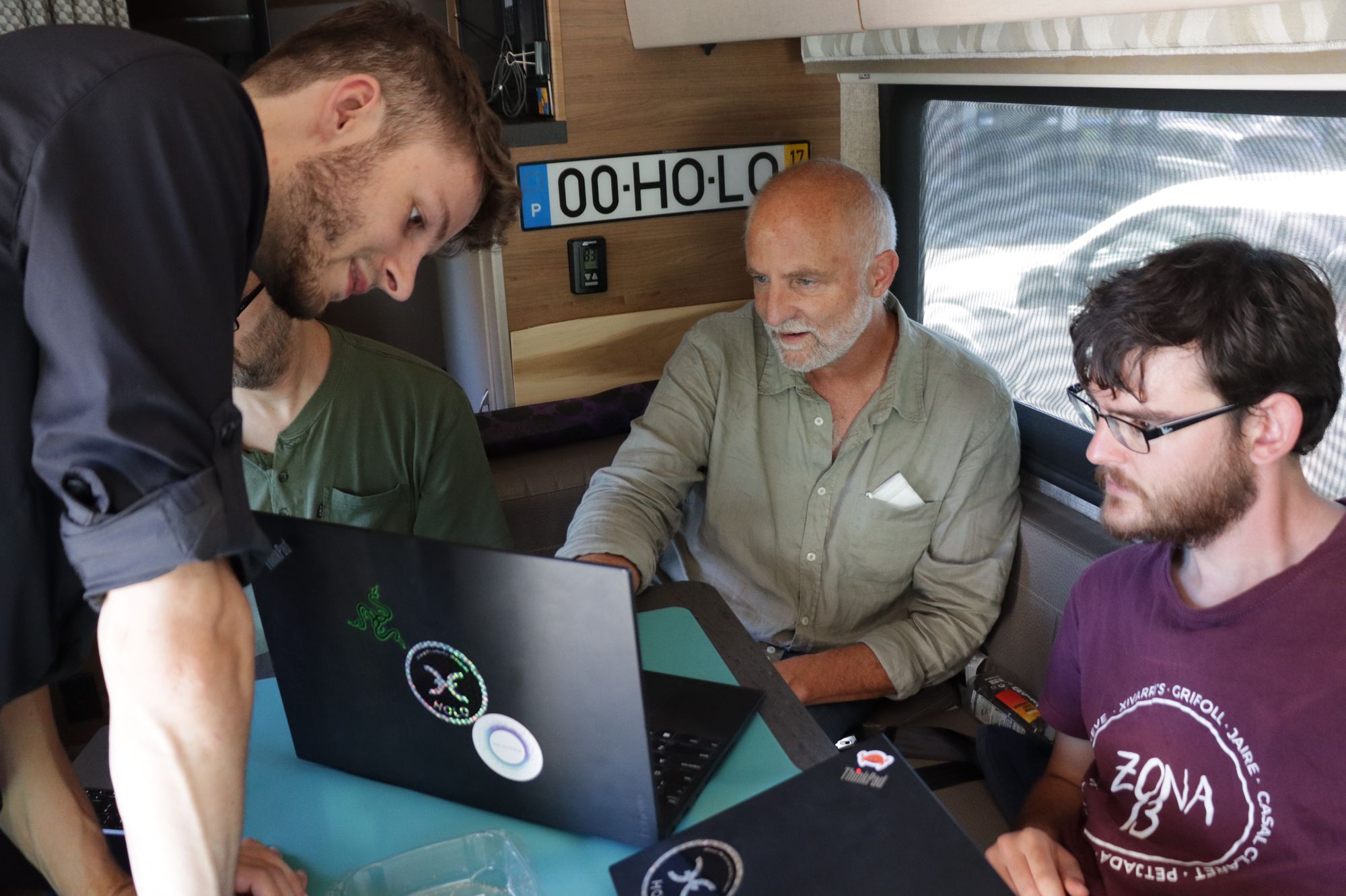 Four developers looking at a laptop in a camper van parked at a gas station